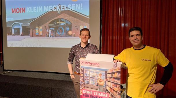 Zwei Männer stehen neben einem Rednerpult und lächeln in die Kamera.