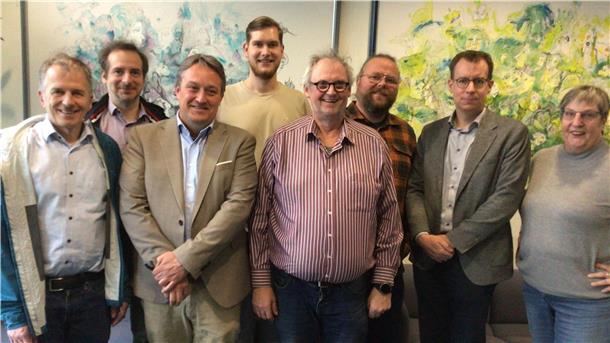 Eine Gruppe von acht Männern und Frauen schaut in die Kamera.