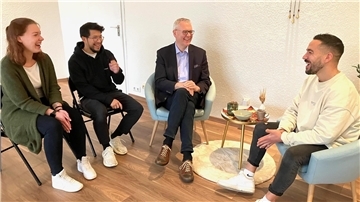 Thümler-Besuch bei Ethictrain: „Herausragendes Projekt“ braucht Hilfe Vier Erwachsene sitzen im Halbkreis und unterhalten sich