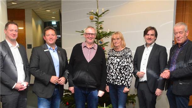 Fünf Männer und eine Frau vor einem Weihnachtsbaum