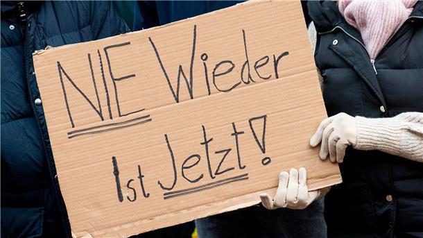 Teilnehmer einer Demonstration gegen Rechtsextremismus unter dem Motto „Nie wieder ist jetzt“ halten ein Schild.