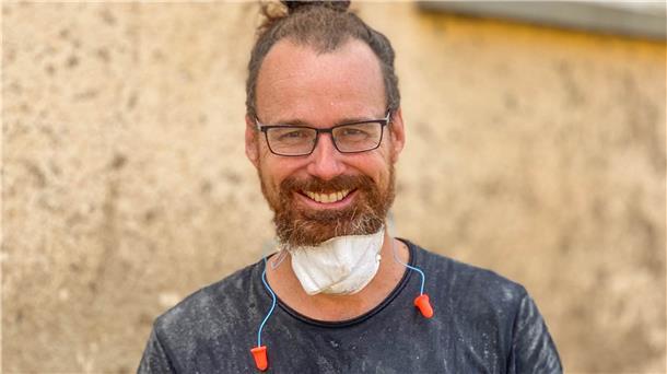 Mann mit Brille, Maske und Ohrstöpseln in dreckigem T-Shirt.