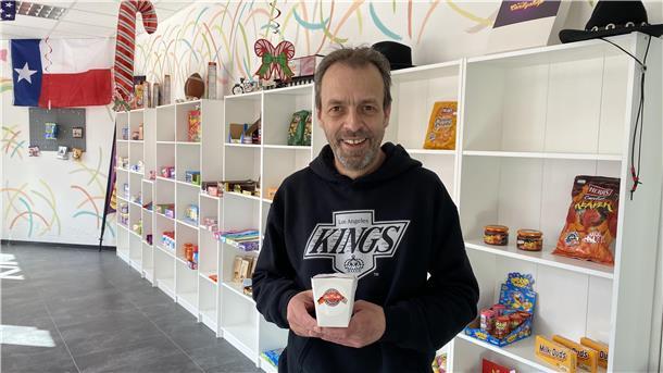 Ein Mann steht in einem Laden und hält eine Packung Eis in der Hand.