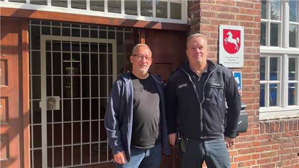 Zwei Männer vor einem Eingang mit Gittertür