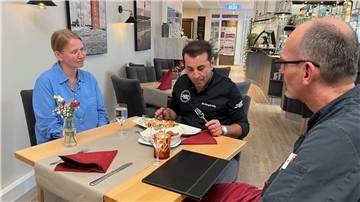 Eine Frau und zwei Männer sitzen an einem Tisch in einem Restaurant.