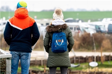 Urlauber blicken an der Nordsee vom Deich aus auf Wohnmobile.