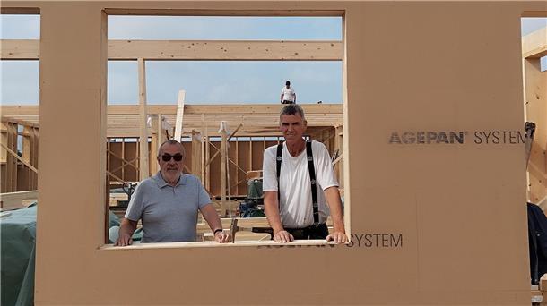 Neubau der TSG Burhave schreitet schnell voran Zwei Männer schauen durch die Fensteröffnung einer Wand in Holzrahmenbauweise