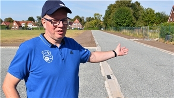 Mann in einem blauen Polohemd und eine Kappe auf einem Sportplatz