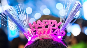 Eine Frau trägt ein Haarband mit der Aufschrift: Happy New Year".