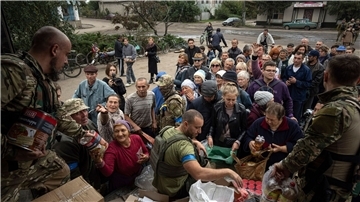 Ukrainische Soldaten verteilen Lebensmittel an an die Einwohner von Isjum.
