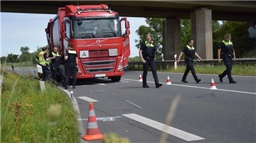 Ein Lkw steht auf einer Bundesstraße, davor sind mehrere Polizisten zu sehen.