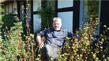 Umzingelt von Lindenblättern sitzt Frits Deemter auf einem Thron aus dem Stumpf einer alten Linde.