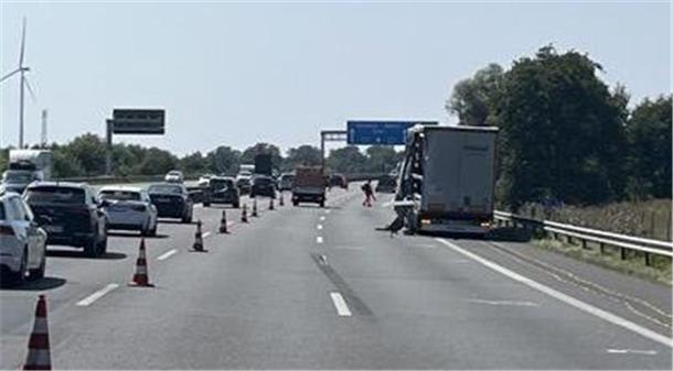 Auf einer dreispurigen Straße steht rechts ein LKW. Die linke Spur ist abgesperrt und dort fahren hintereinander mehrere Autos.