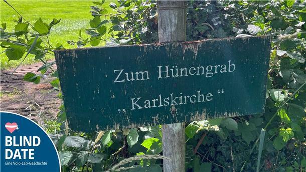 Wegweiser neben einem Feld. Zu lesen ist darauf: zum Hünengrab „Karlskirche“.