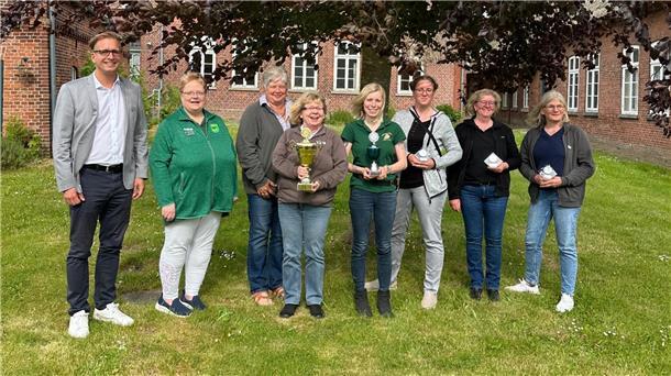 Ein Mann und sieben Frauen stehen zum Gruppenbild auf einem rasen