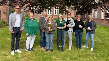 Ein Mann und sieben Frauen stehen zum Gruppenbild auf einem rasen
