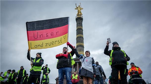 „Unser Land zuerst!“ - Teilnehmer der Großkundgebung protestieren mit einer Deutschlandfahne vor der Siegerssäule.