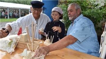 Zwei Männer und ein Mädchen bauen aus Holz einen Kutter.