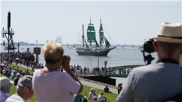 Menschen schauen sich in Bremerhaven die Einlaufparade der Sail 2025 an.
