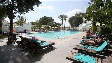 Urlauber entspannen am Swimmingpool eines Hotels in Tunesien.