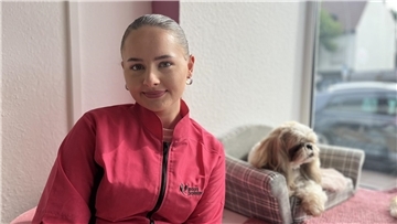 Frau sitzt und neben ihr ein Hund. 