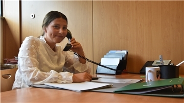 Die Frewillige Vanessa Thomas sitzt beim FC Geestland am Tisch und telefoniert. 