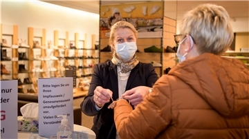 Vereinfachter 2G-Nachweis: Andrea von Kampen vom Schuhhaus Fuss in Geestemünde verteilt auf Wunsch die Bremerhaven-Bändchen an ihre Kunden. Foto: Ralf Masorat