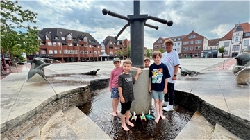 Kinder an einer Wasserstelle. Viel Spaß hatten die Kinder am Montag mit ihren Booten am Brunnen in der Innenstadt.