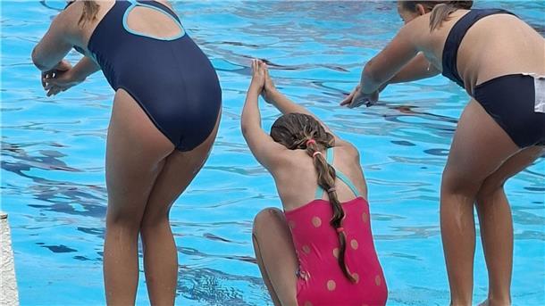 Kinder und Jugendliche springen in ein Schwimmbecken