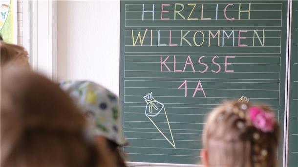 Familien kämpfen: Vom einfachen Schulstart zum teuren Pflichtprogramm  „Herzlich willkommen Klasse1 A“ steht an der Tafel eines Klassenzimmers