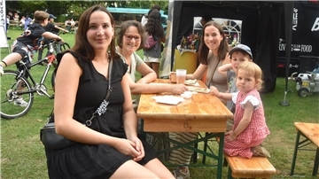 Drei Frauen und zwei Kinder sitzen an einer Bierzeltgarnitur und lächeln in die Kamera.