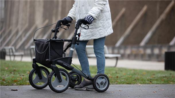 Das Foto zeigt eine Frau mit Rollator. 