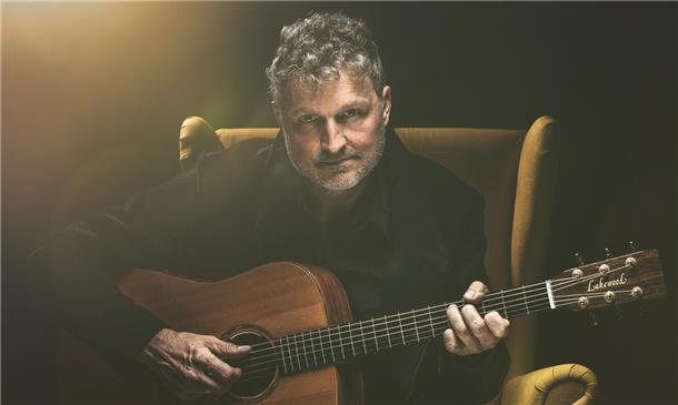 Volker Rechin spielt in Selsingen in seinem gelben Sessel solo an der Gitarre unter anderem Songs seiner Band 3 Miles To Essex.