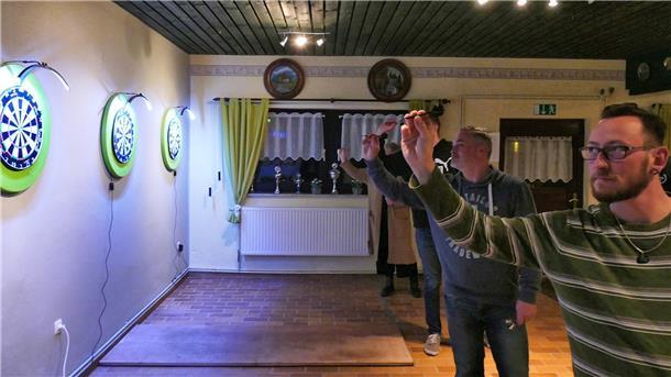 Vier Dartspieler des Schützenverein Mulsum zielen im Clubraum auf ihre Dartscheiben.