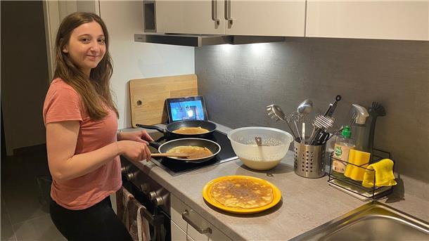 Frau steht in der Küche und kocht.