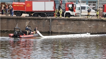 Vom Rettungsboot aus richtet die Feuerwehr im Neuen Fischereihafen eine Ölsperre mit einem Ölschlängel ein.