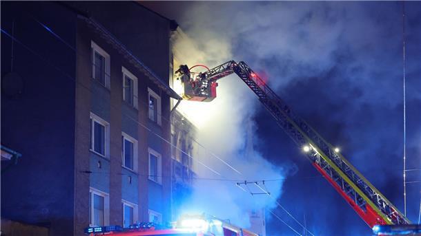 Von einer Drehleiter aus bekämpft ein Feuerwehrmann den Brand in dem Mehrfamilienhaus.