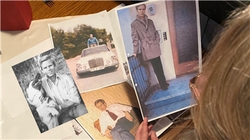 Eine Person betrachtet mehrere Fotos von Kurt-Werner Wichmann.