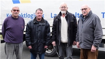 Vier Männer stehen vor einem LKW.
