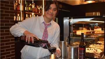 Eine junge Frau gießt Wein in ein Glas.