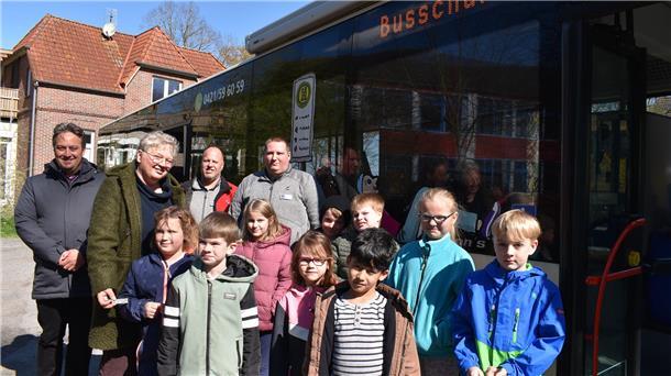 Hier lernen Kinder, wie man richtig Bus fährt Vor der Bus-Schule in Schweiburg: Kinder der zweiten Grundschulklasse mit Lehrerin Ilka Harjehusen, den beiden Bus-Schule-Trainern André Gieschen und Sebastian Jacobs sowie VBW-Geschäftsführer Andreas Jung (links).