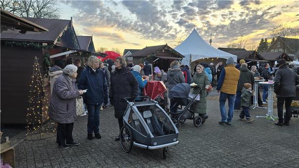 Weihnachtlich geschmückter Marktplatz mit Buden, Hütten und Menschen jeden Alters.