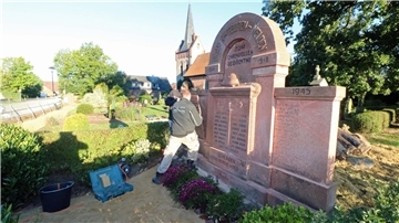 Ein Mann befestigt eine Marmortafel an einem Denkmal.