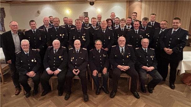 Gruppenbild von Feuerwehrkameraden der Freiwilligen Feuerwehr Loxstedt in Uniform, aufgenommen bei der Ehrungsveranstaltung in einem festlich dekorierten Saal. In mehreren Reihen sitzen und stehen die geehrten Mitglieder sowie Führungskräfte.