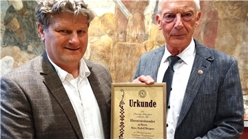 Vorsitzender Karsten Hinrichs (links) überreicht seinem Vorgänger Hans-Rudolf Mengers die Ehrenurkunde.