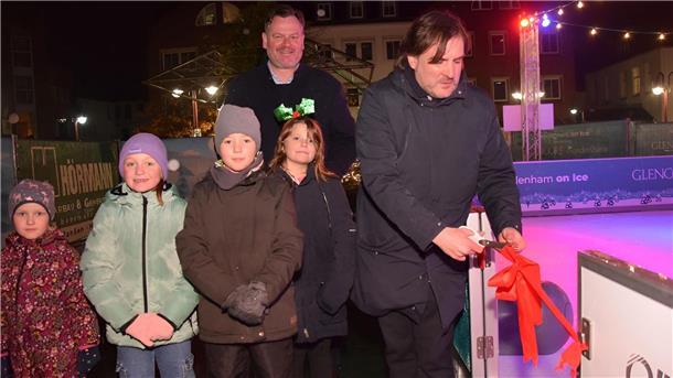Vier Kinder und zwei Männer an einer Eisbahn
