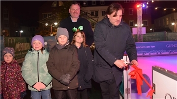 Vier Kinder und zwei Männer an einer Eisbahn