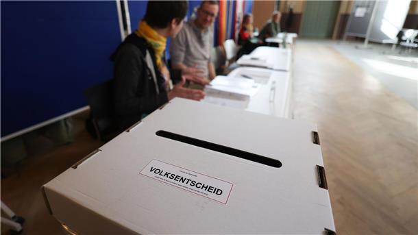Wahlhelfer sitzen vor einer Wahlurne in einem Wahllokal in Berlin-Weissensee.