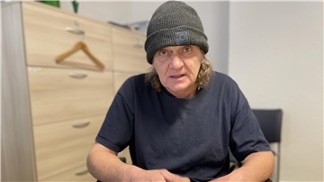 Mann mit Mütze in einem blauen T-Shirt.