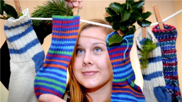 Eine Frau hängt Socken mit kleinen Präsenten an eine Leine